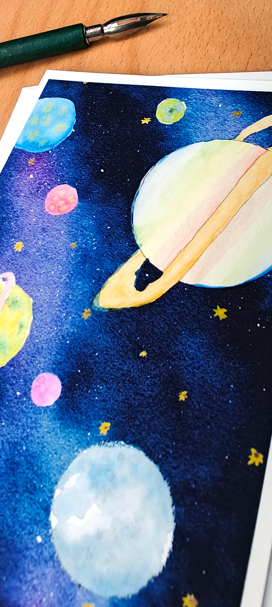 Space-themed artwork with planets and stars on a piece of paper, with a pen at the top.