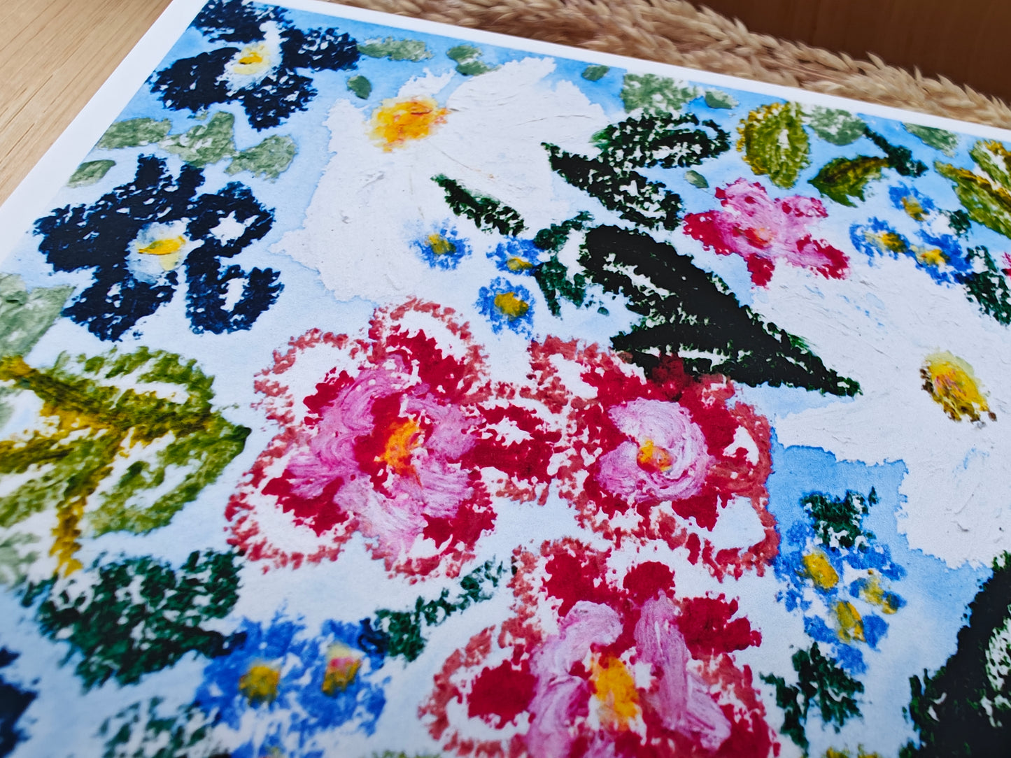Closeup of postcard with floral illustration on oil pastel and watercolour on a wooden surface