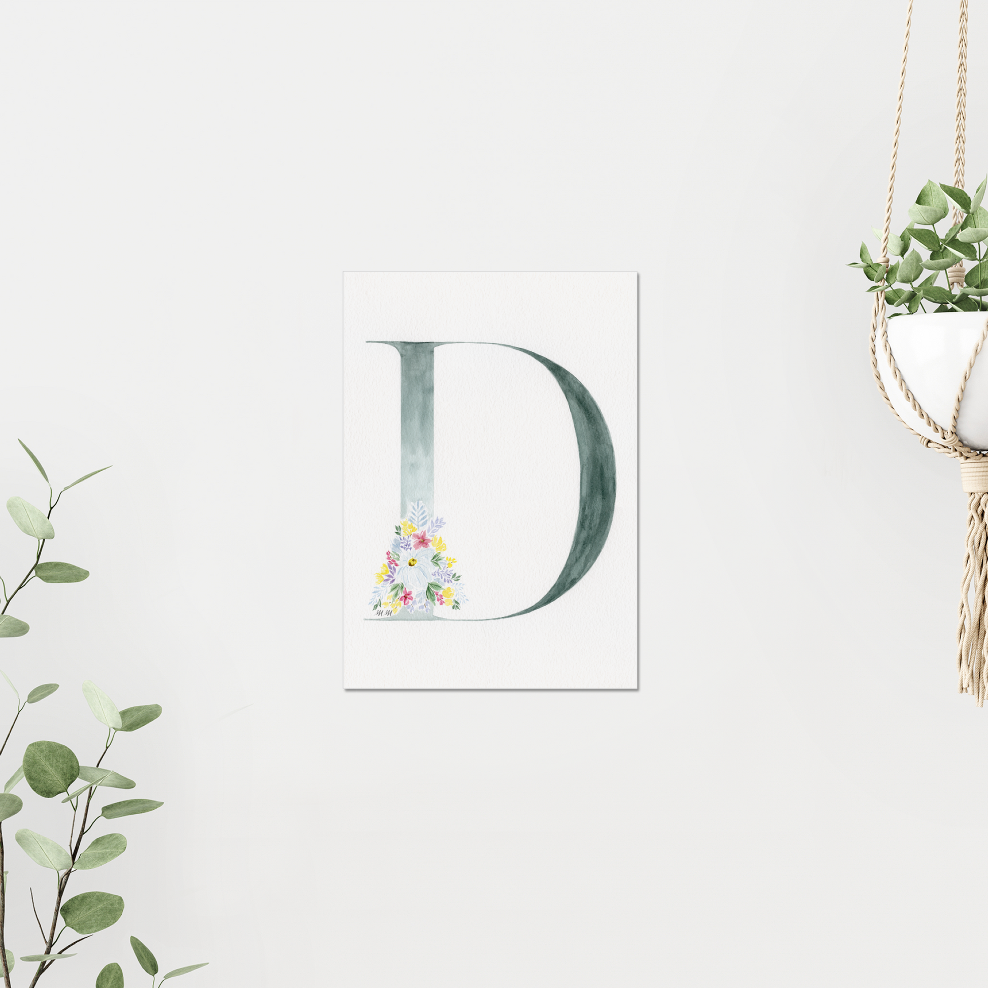Decorative letter 'D' with floral design on a white background, surrounded by greenery. Made with watercolours.