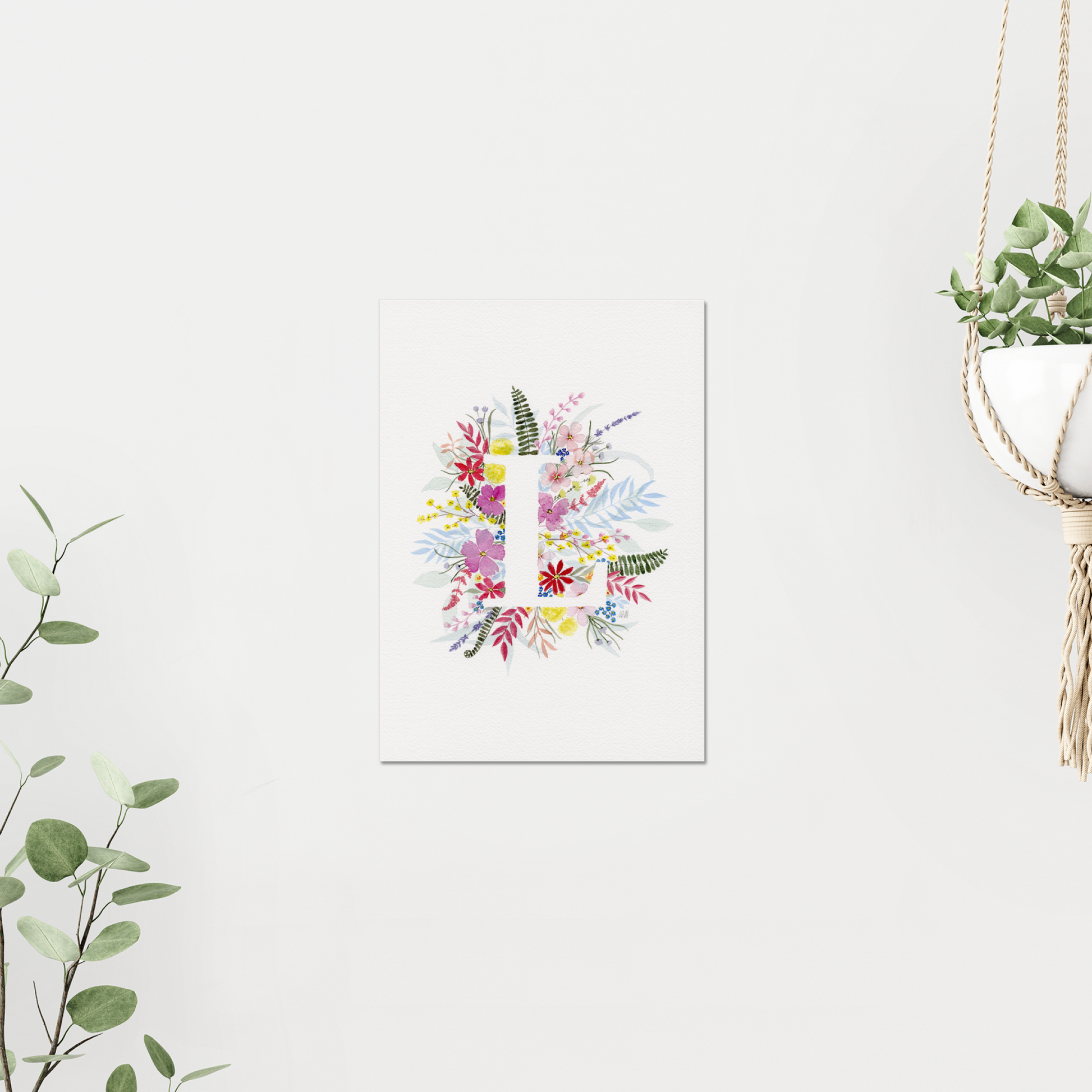 Letter 'L' made of colourful flowers and leaves on a white background. Made with watercolours. Artwork on a white wall with greenery accents.