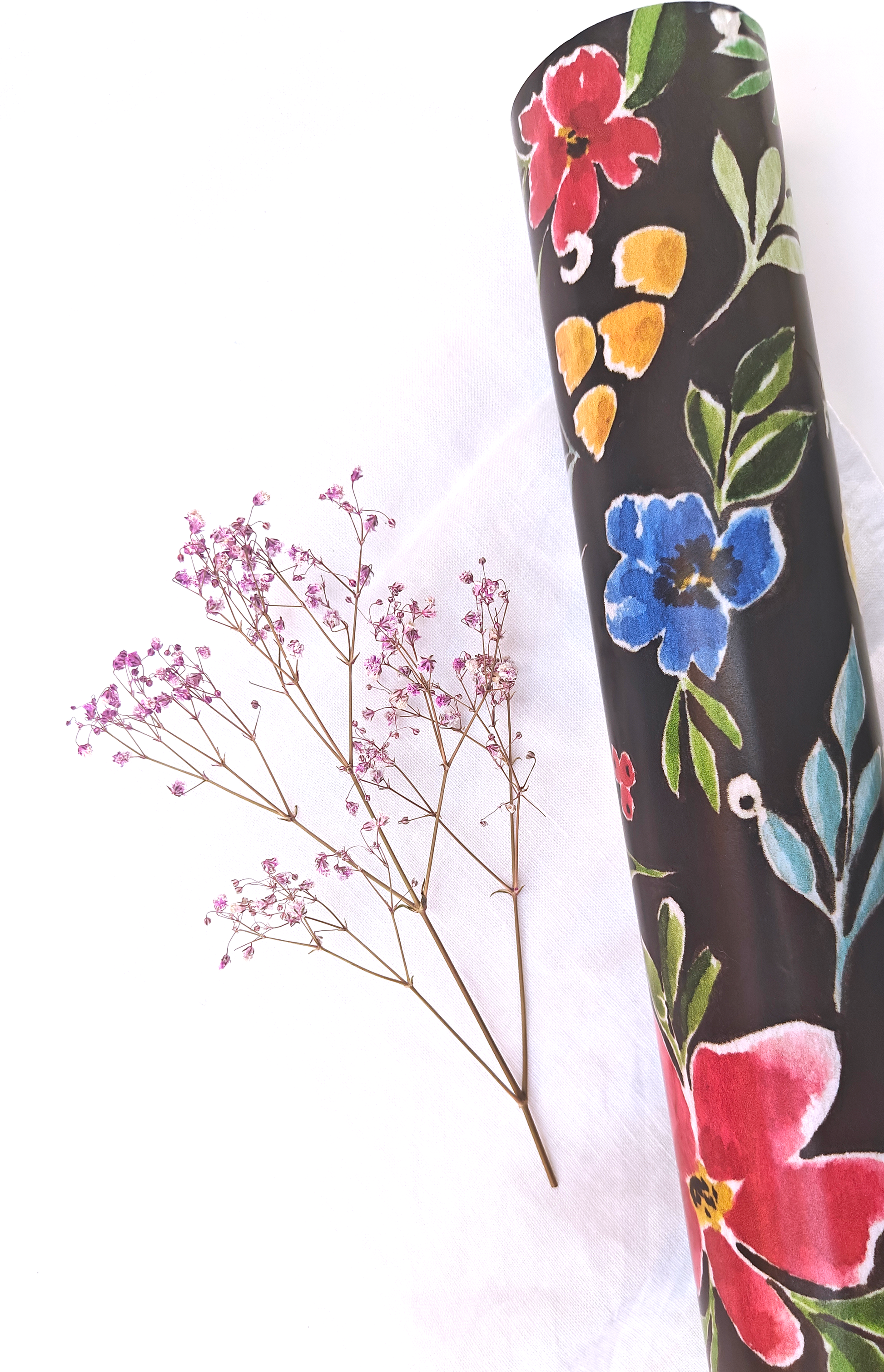 Floral-patterned wrapping paper on a white background with dried flowers.