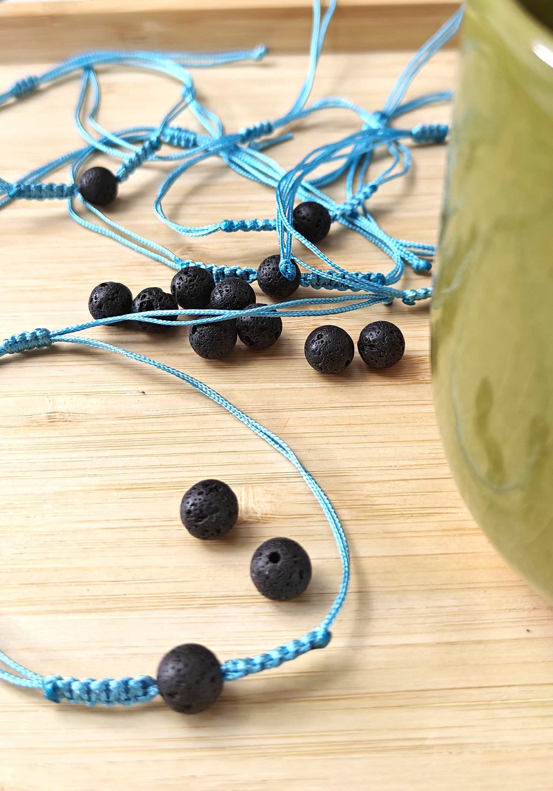 Blue bracelets with black lava stone bead on a wooden surface.
