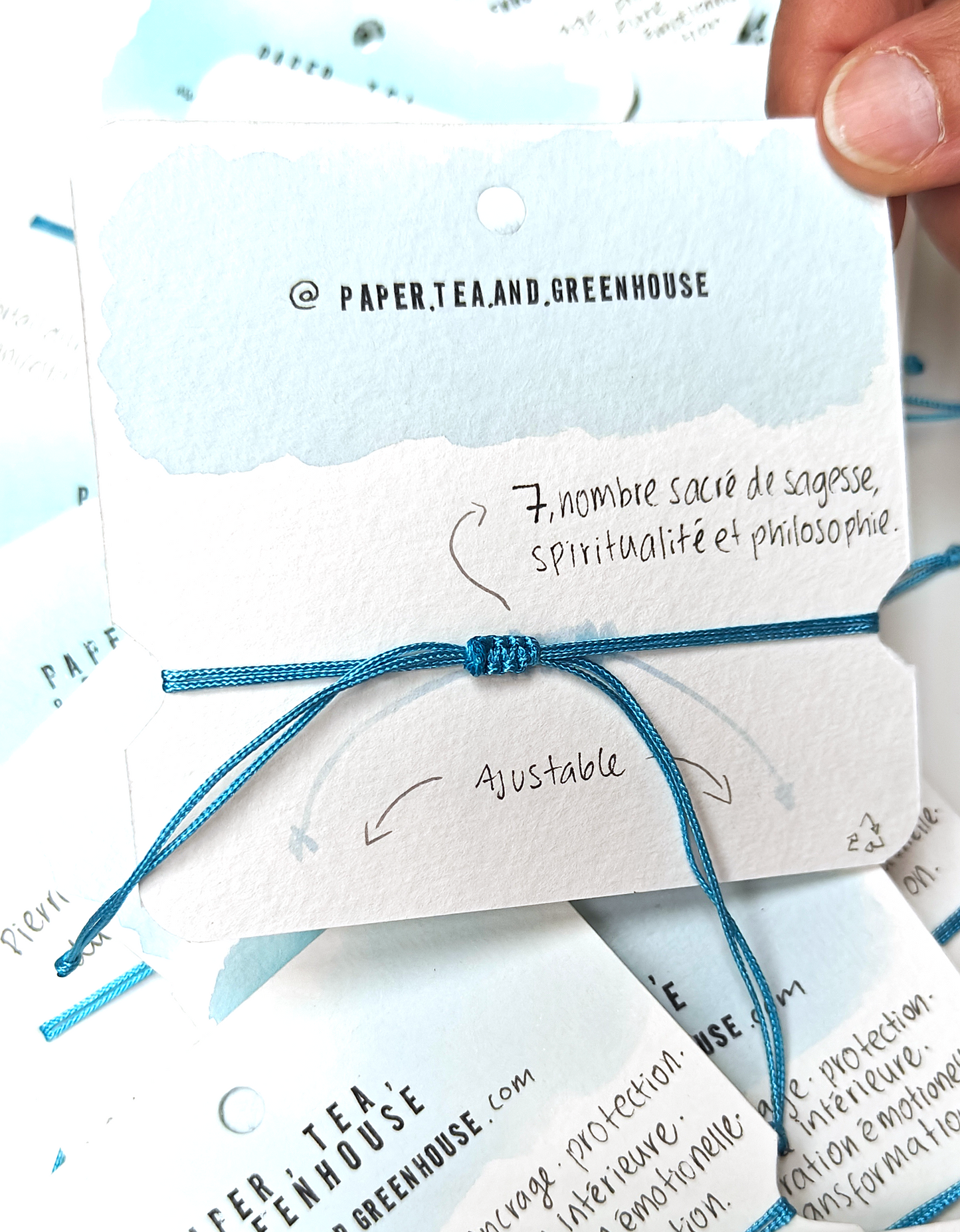 A bracelet with a smooth volcanic stone in the centre, surrounded by turquoise polyester cord knotted by hand with meaning and precision. The spiritual bracelet is in it's packaging, also made by hand where we can find all the meanings.