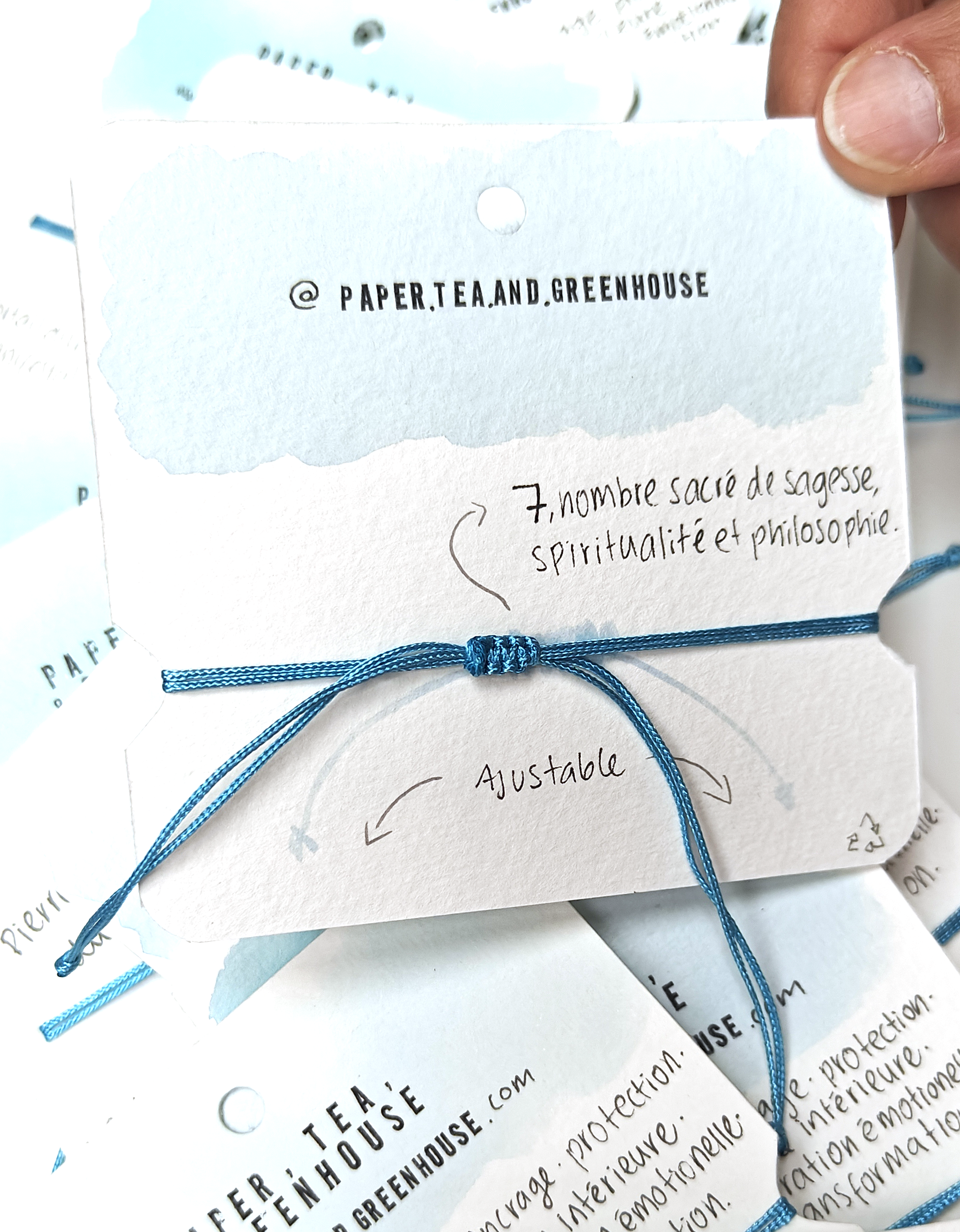 A bracelet with a smooth volcanic stone in the centre, surrounded by turquoise polyester cord knotted by hand with meaning and precision. The spiritual bracelet is in it's packaging, also made by hand where we can find all the meanings.