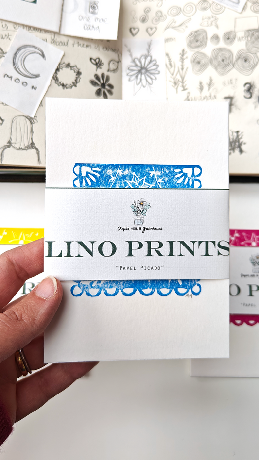 Hand holding a pack of 'Lino Prints' celebrating Mexican Papel Picado with a background of sketched materials.