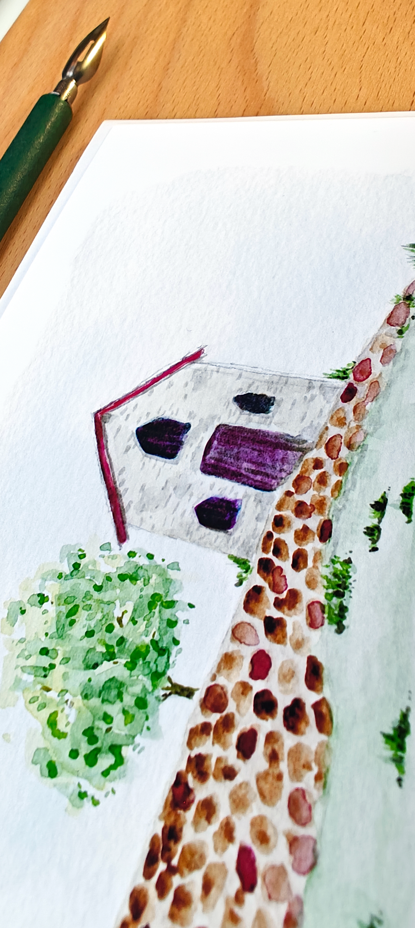 Watercolour of a house with a tree on a white post card.