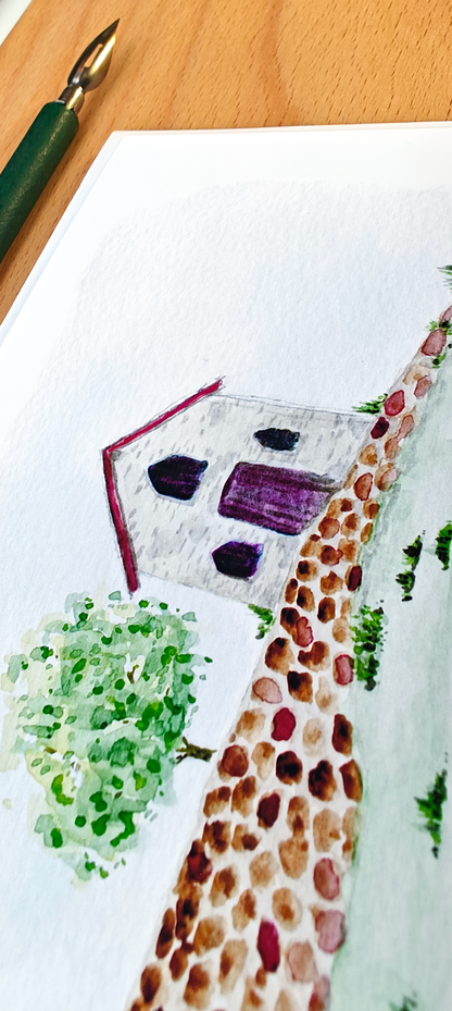 Watercolour of a house with a tree on a white post card.