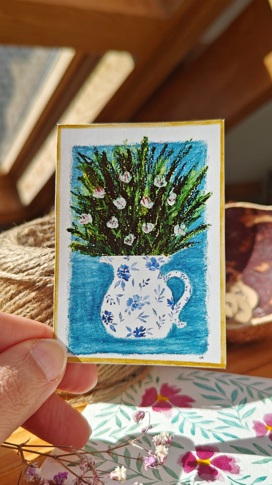 Sticker of an oil pastel and watercolour painting of a decorated, white pitcher with flowers and greenery held by a hand